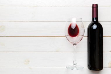 Bir bardak kırmızı şarap ve renkli masada bir şişe. Düz konum, üst görünüm kopyalama alanı.