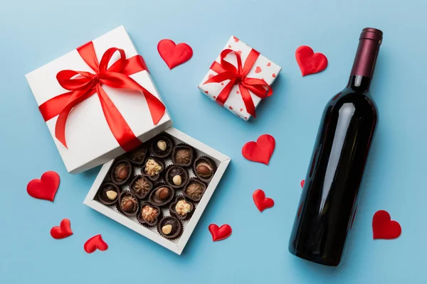 ギフトとチョコレートでバレンタインデーのための色の背景に赤ワインのボトル ハート型にチョコレートトップビューのギフトボックス付きコピースペース — ストック写真