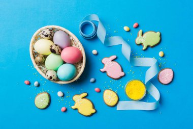 Renkli paskalya kurabiyeleri sepette renkli arka planda çok renkli Paskalya yumurtaları. Pastel renginde Paskalya yumurtası. Kopyalama alanı olan tatil kavramı.