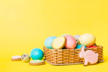 Renkli paskalya kurabiyeleri sepette renkli arka planda çok renkli Paskalya yumurtaları. Pastel renginde Paskalya yumurtası. Kopyalama alanı olan tatil kavramı.