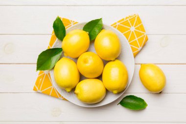 Taze kesilmiş limon ve tüm limonları renkli arka planda yuvarlak tabakta. Yemek ve içecek malzemeleri hazırlanıyor. Sağlıklı beslenme teması üst görünüm kopyalama alanı.
