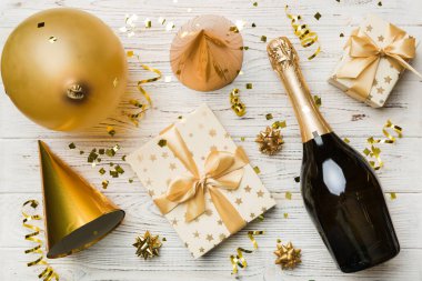 Renkli arka planda şampanya şişesi hediye paketi kurdeleleri ve konfetilerin düz kompozisyonu vardı. Düz konum, üst görünüm tatil konsepti.