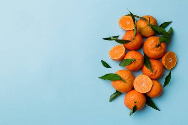 Renkli arkaplanda yeşil yaprakları, üst görünümü, metin için alanı olan bir sürü olgun mandalina..