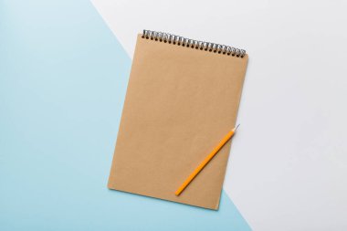 Renkli bir arka planda okul kahverengi defteri, bir masadaki spiral el işi not defteri..