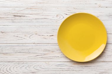 Ahşap arka planda boş sarı tabağın üst görüntüsü. Tasarımın için boş boşluk.