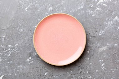 Çimento arka planındaki boş pembe tabağın üst görüntüsü. Tasarımın için boş boşluk.