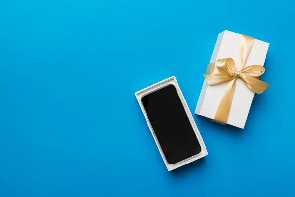 Gesloten Geschenkdoos Met Gouden Lint Smartphone Kleur Achtergrond Bovenaanzicht Blanco — Stockfoto