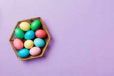 Renkli arka planda dokuma sepetinde çok renkli Paskalya yumurtaları. Pastel renginde Paskalya yumurtası. Kopyalama alanı olan tatil kavramı.