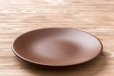 Ahşap zemindeki boş tabağın perspektif görüntüsü. Tasarımın için boş boşluk.