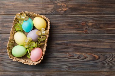 Renkli arka planda dokuma sepetinde çok renkli Paskalya yumurtaları. Pastel renginde Paskalya yumurtası. Kopyalama alanı olan tatil kavramı.