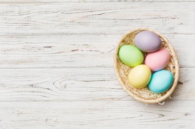 Renkli arka planda dokuma sepetinde çok renkli Paskalya yumurtaları. Pastel renginde Paskalya yumurtası. Kopyalama alanı olan tatil kavramı.