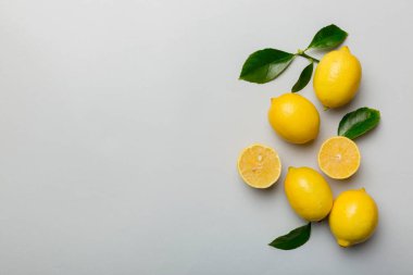 Renkli arka planda yeşil yapraklı taze limonlar, üst görünüm, metin için boşluk.