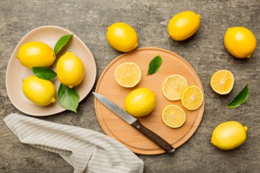 Kesme tahtasındaki taze ve olgun limonlar için fotokopi alanı olan üst manzara. Sağlıklı yemek geçmişi. Limon ve limon dilimlerinin, sıkacağı ve bıçak renginde arka planı çok zarif..