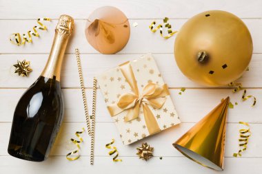 Renkli arka planda şampanya şişesi hediye paketi kurdeleleri ve konfetilerin düz kompozisyonu vardı. Düz konum, üst görünüm tatil konsepti.