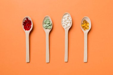 Renkli arka planda tahta kaşıkta vitamin ve mineral haplarının üst görünümü. Muhtelif ilaç haplarının en üst görüntüsü. Beslenme takviyesi sağlık ürünleri.
