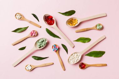 Renkli arka planda tahta kaşıkta vitamin ve mineral haplarının üst görünümü. Muhtelif ilaç haplarının en üst görüntüsü. Beslenme takviyesi sağlık ürünleri.