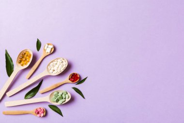 Renkli arka planda tahta kaşıkta vitamin ve mineral haplarının üst görünümü. Muhtelif ilaç haplarının en üst görüntüsü. Beslenme takviyesi sağlık ürünleri.