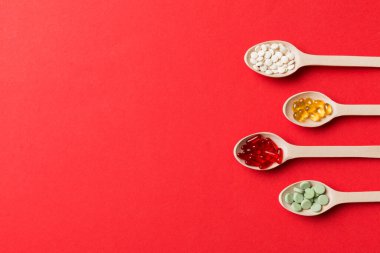 Renkli arka planda tahta kaşıkta vitamin ve mineral haplarının üst görünümü. Muhtelif ilaç haplarının en üst görüntüsü. Beslenme takviyesi sağlık ürünleri.