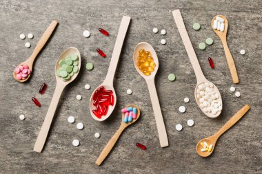 Renkli arka planda tahta kaşıkta vitamin ve mineral haplarının üst görünümü. Muhtelif ilaç haplarının en üst görüntüsü. Beslenme takviyesi sağlık ürünleri.
