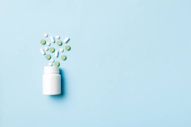Renkli arka planda plastik şişede çok renkli haplar ve kapsüller, kopyalama alanı. Çeşitli ilaç tabletleri ve haplar, vitamin ve besin takviyeleri kavramı.