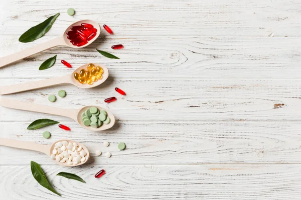 Renkli arka planda tahta kaşıkta vitamin ve mineral haplarının üst görünümü. Muhtelif ilaç haplarının en üst görüntüsü. Beslenme takviyesi sağlık ürünleri.