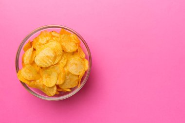 Renkli arka planda izole edilmiş patates cipsi. Lezzetli çıtır patates cipsi kasede. Mesaj için yer var. Üst görünüm.