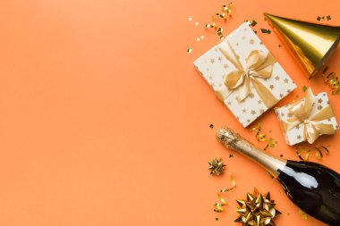 Renkli arka planda şampanya şişesi hediye paketi kurdeleleri ve konfetilerin düz kompozisyonu vardı. Düz konum, üst görünüm tatil konsepti.