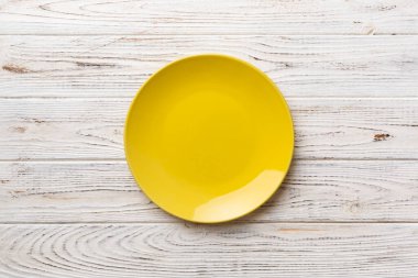 Ahşap arka planda boş sarı tabağın üst görüntüsü. Tasarımın için boş boşluk.