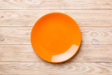 Ahşap arka planda boş turuncu tabağın üst görüntüsü. Tasarımın için boş boşluk.