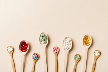 Renkli arka planda tahta kaşıkta vitamin ve mineral haplarının üst görünümü. Muhtelif ilaç haplarının en üst görüntüsü. Beslenme takviyesi sağlık ürünleri.