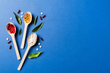 Renkli arka planda tahta kaşıkta vitamin ve mineral haplarının üst görünümü. Muhtelif ilaç haplarının en üst görüntüsü. Beslenme takviyesi sağlık ürünleri.