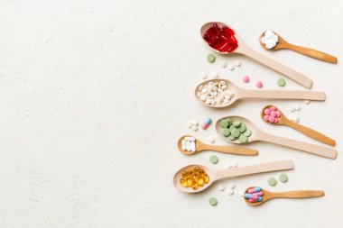 Renkli arka planda tahta kaşıkta vitamin ve mineral haplarının üst görünümü. Muhtelif ilaç haplarının en üst görüntüsü. Beslenme takviyesi sağlık ürünleri.