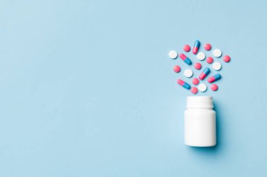 Renkli arka planda plastik şişede çok renkli haplar ve kapsüller, kopyalama alanı. Çeşitli ilaç tabletleri ve haplar, vitamin ve besin takviyeleri kavramı.