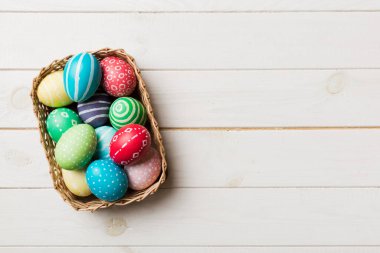 Renkli arka planda dokuma sepetinde çok renkli Paskalya yumurtaları. Pastel renginde Paskalya yumurtası. Kopyalama alanı olan tatil kavramı.