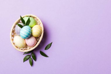 Renkli arka planda dokuma sepetinde çok renkli Paskalya yumurtaları. Pastel renginde Paskalya yumurtası. Kopyalama alanı olan tatil kavramı.