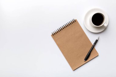 Defterli modern ofis masası ve bir fincan kahveli diğer malzemeler. Tasarım için boş defter sayfası. Üst manzara, düz uzanma.