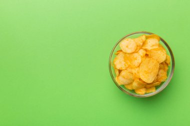 Renkli arka planda izole edilmiş patates cipsi. Lezzetli çıtır patates cipsi kasede. Mesaj için yer var. Üst görünüm.