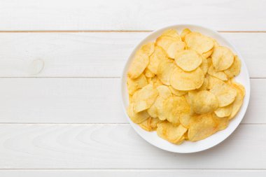 Renkli arka planda izole edilmiş patates cipsi. Lezzetli çıtır patates cipsi kasede. Mesaj için yer var. Üst görünüm.