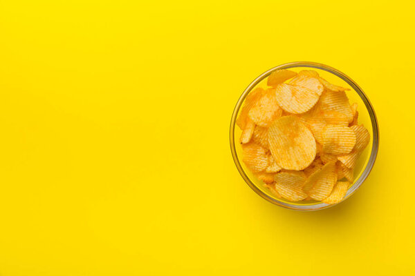 Картофельные чипсы на миске изолированы на цветном фоне. Вкусные хрустящие чипсы в миске. Пространство для текста. Вид сверху.