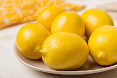 Taze kesilmiş limon ve tüm limonları renkli arka planda yuvarlak tabakta. Yemek ve içecek malzemeleri hazırlanıyor. Sağlıklı beslenme teması üst görünüm kopyalama alanı.