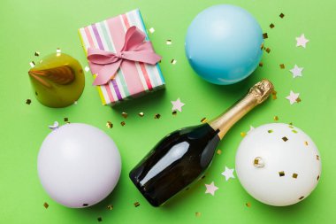 Renkli arka planda şampanya şişesi hediye paketi kurdeleleri ve konfetilerin düz kompozisyonu vardı. Düz konum, üst görünüm tatil konsepti.