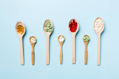 Renkli arka planda tahta kaşıkta vitamin ve mineral haplarının üst görünümü. Muhtelif ilaç haplarının en üst görüntüsü. Beslenme takviyesi sağlık ürünleri.