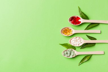 Renkli arka planda tahta kaşıkta vitamin ve mineral haplarının üst görünümü. Muhtelif ilaç haplarının en üst görüntüsü. Beslenme takviyesi sağlık ürünleri.