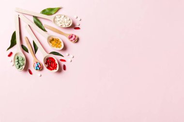 Renkli arka planda tahta kaşıkta vitamin ve mineral haplarının üst görünümü. Muhtelif ilaç haplarının en üst görüntüsü. Beslenme takviyesi sağlık ürünleri.