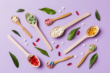 Renkli arka planda tahta kaşıkta vitamin ve mineral haplarının üst görünümü. Muhtelif ilaç haplarının en üst görüntüsü. Beslenme takviyesi sağlık ürünleri.