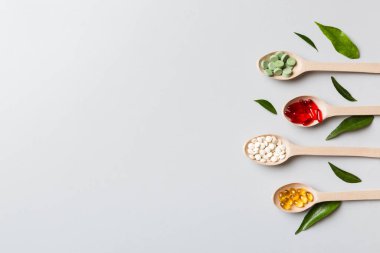 Renkli arka planda tahta kaşıkta vitamin ve mineral haplarının üst görünümü. Muhtelif ilaç haplarının en üst görüntüsü. Beslenme takviyesi sağlık ürünleri.