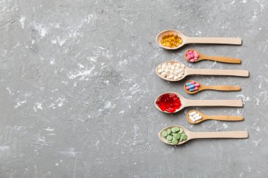 Renkli arka planda tahta kaşıkta vitamin ve mineral haplarının üst görünümü. Muhtelif ilaç haplarının en üst görüntüsü. Beslenme takviyesi sağlık ürünleri.