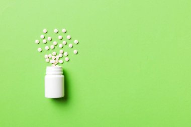 Renkli arka planda plastik şişede çok renkli haplar ve kapsüller, kopyalama alanı. Çeşitli ilaç tabletleri ve haplar, vitamin ve besin takviyeleri kavramı.