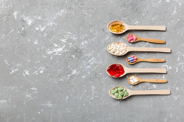 Renkli arka planda tahta kaşıkta vitamin ve mineral haplarının üst görünümü. Muhtelif ilaç haplarının en üst görüntüsü. Beslenme takviyesi sağlık ürünleri.