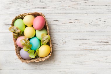 Renkli arka planda dokuma sepetinde çok renkli Paskalya yumurtaları. Pastel renginde Paskalya yumurtası. Kopyalama alanı olan tatil kavramı.